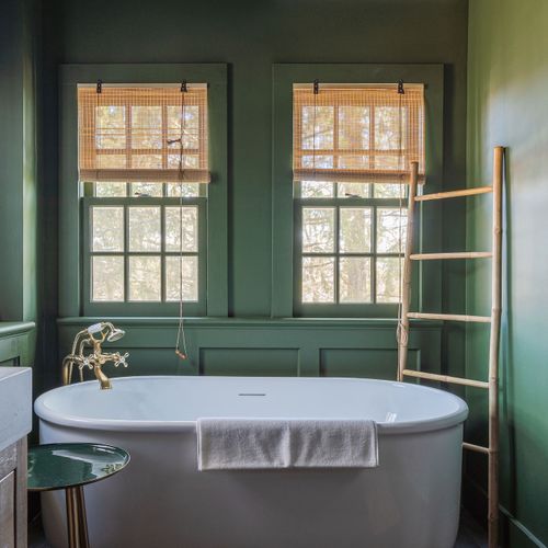 The green bathroom off the kitchen is complete with a beautiful bath tub, walk-in shower, and brass fixtures throughout.