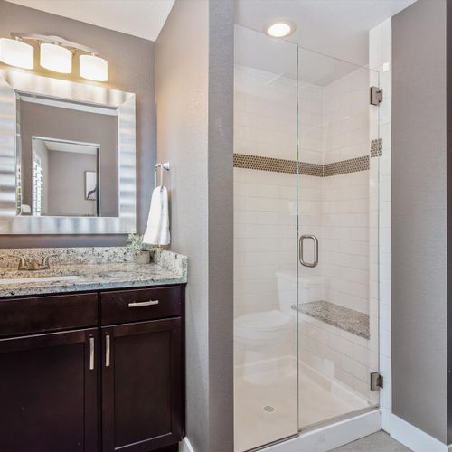 This upgraded bathroom features a single vanity with stone counters and an enclosed glass shower. Each bathroom is supplied with hotel-quality towels, complimentary shampoo, conditioner and body wash.