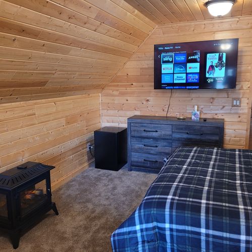 BEDROOM #3 (SECOND FLOOR BUNK ROOM ABOVE GARAGE):  Features 2 queen-size beds, a comfy chair, wall A/C unit, wall heater, electric fireplace, 2 nightstands, a dresser, mini refrigerator, and live streaming television (via Sling).