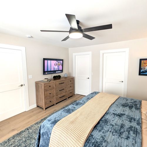 BEDROOM #1 (PRIMARY BEDROOM, MAIN FLOOR):  This is large and beautiful bed featuring a king-size bed, private ensuite full bathroom, private television, dresser, chair, ceiling fan, and closet.