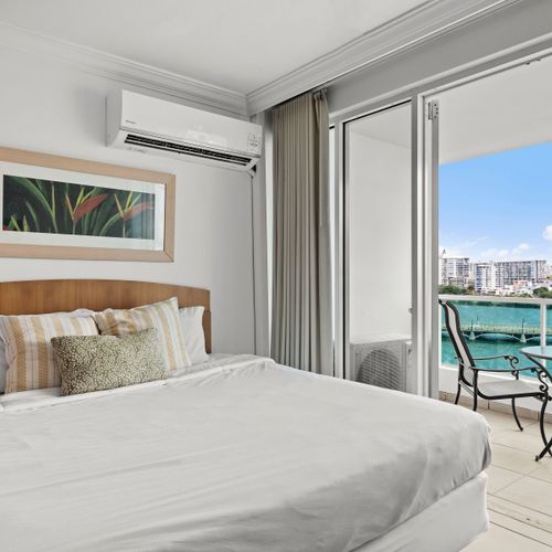 Relax in comfort on your plush, king-sized bed, featuring serene decor and ample light.