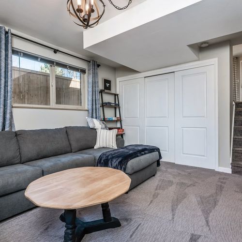 - secondary living space features large sectional cozy blanket and open shelving
- double door closet adds convenient storage for longer guest stays
- bright windows carpeted floor and casual seating make it a perfect hangout