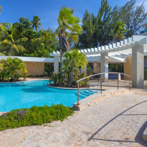 Dive into paradise! Our sparkling pool is surrounded by lush tropical landscaping, offering a refreshing escape and a perfect spot for sunbathing and relaxation.