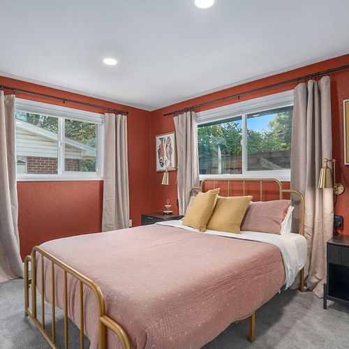 An inviting upstairs bedroom adorned in warm red hues, featuring a cozy bed and stylish decor for a restful retreat.