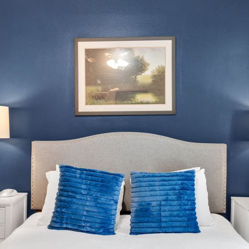 Plush bed w/ tufted headboard & bold blue pillows for a restful night's sleep.