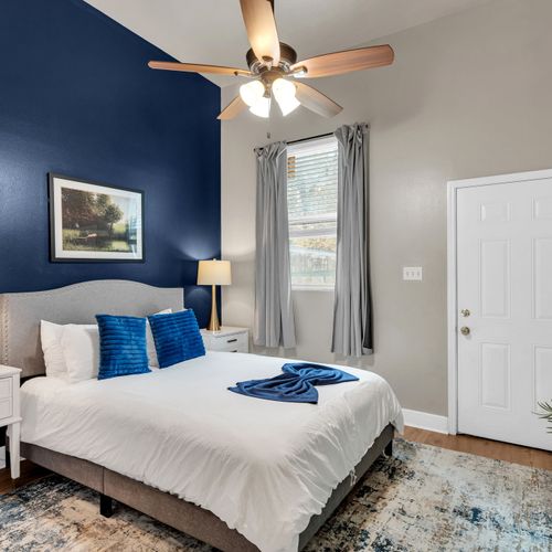 Bright bedroom w/ crisp white bedding & warm natural light.