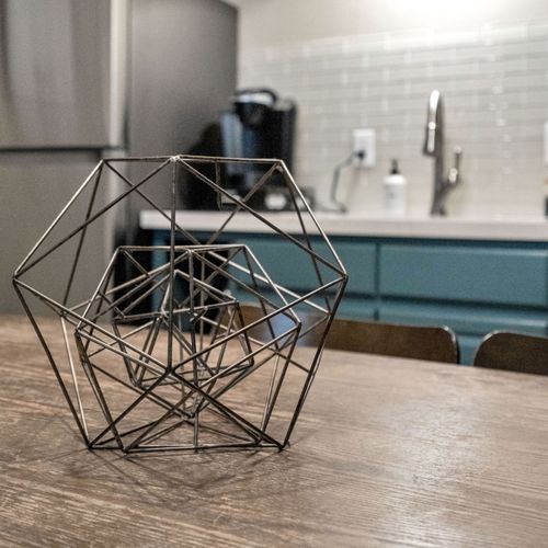 Geometric light fixture & teal kitchen details adding a modern artistic touch.