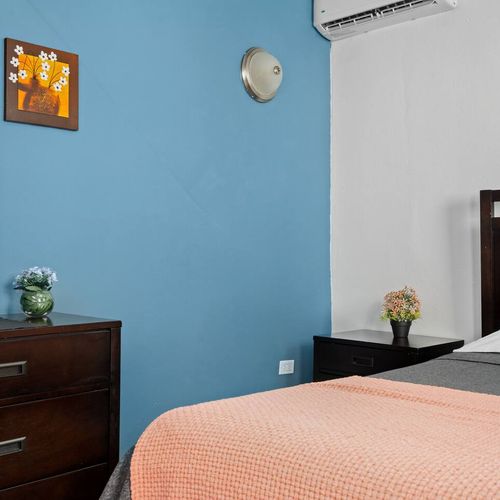A peaceful sanctuary is ready for you, blending modern style with coziness, showcasing a roomy bed and a sophisticated dressing mirror.