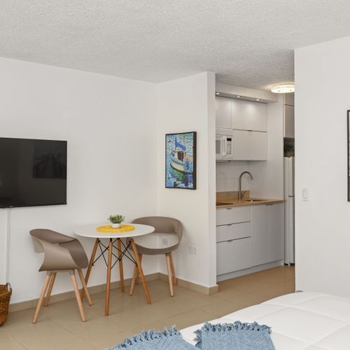 beachfront studio with smart tv, queen sized bed, dining table, and kitchen with appliances and fridge