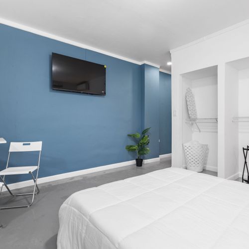 Dormitorio acogedor y moderno con una pared decorativa en azul intenso y un televisor de pantalla plana montado.