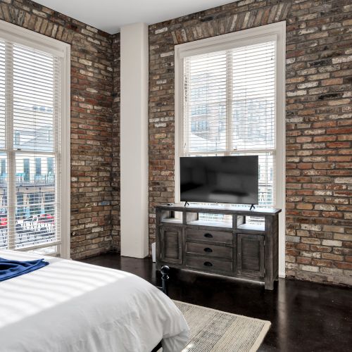 Cozy corner bedroom w/ charming exposed brick & warm-toned decor.