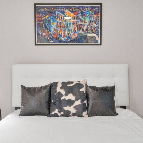 Sunlit bedroom w/ bold artwork & cozy bedding to wake up feeling refreshed.