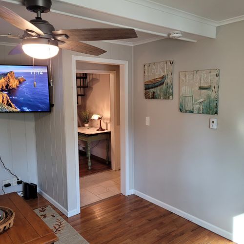 Living room:  comfy living room with a sofa, gas fireplace, live streaming television, coffee table, comfy chair, and ceiling fan.