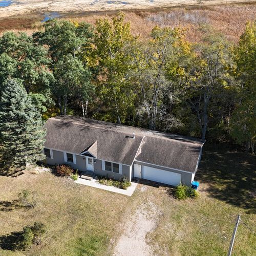 EXTERIOR:  Aerial photo of the home in late summer with the Betsie River in the background