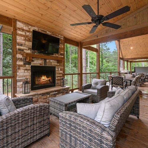 Covered patio has outdoor seating around the fireplace and tv!