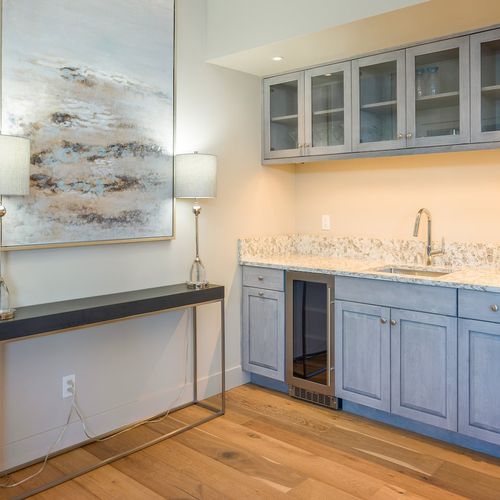 Evening cocktails are made easy with a wine cooler, drinkware, and sink at the custom wet bar.