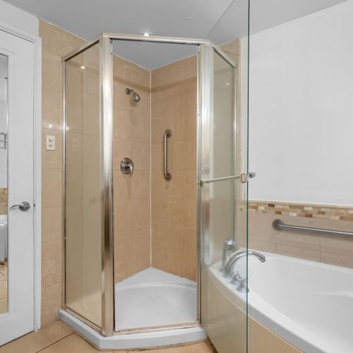 Experience comfort and convenience in this well-appointed bathroom, offering both a spacious walk-in shower and a corner bathtub for your relaxation needs.