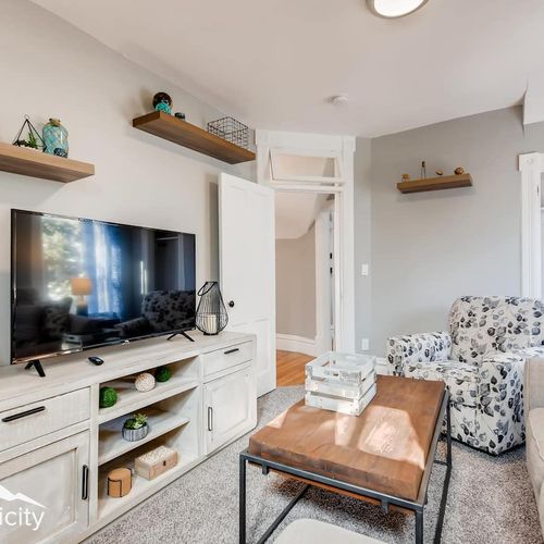 - comfy lounge with floral accent chair, large smart tv, and stylish white console for entertainment
- floating wood shelves showcase playful decor in a soft neutral space
- plush carpet and natural light make this a relaxing movie night retreat