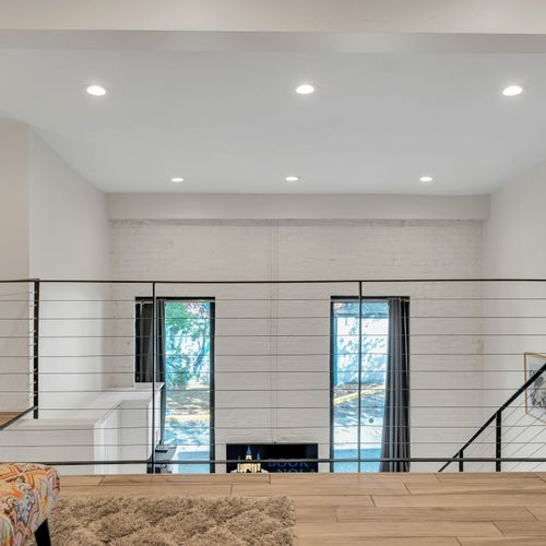 The loft overlooks the bright living space below, with plenty of natural light and modern railings for a sleek, spacious vibe.
