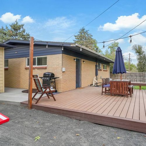- large backyard deck with dining table, umbrella, and bar style seating for two
- string lights overhead create an inviting glow for evening hangouts
- enjoy meals, games, or cocktails outdoors in this fully fenced open air space