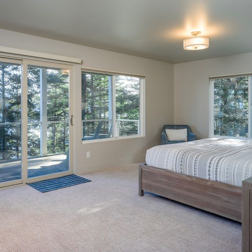 Lower Level Guest bedroom ensuite with a king bed, reading chair, and water views.