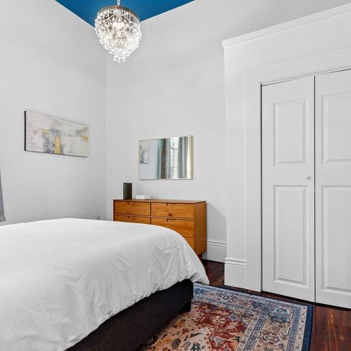 Clean, simple bedroom w/ white walls & natural light — a calm retreat.