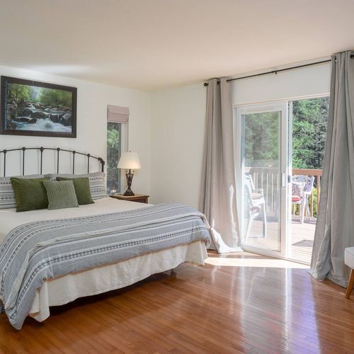 Main Bedroom with a king bed, reading chair, bathroom ensuite and walk-out doors to deck.