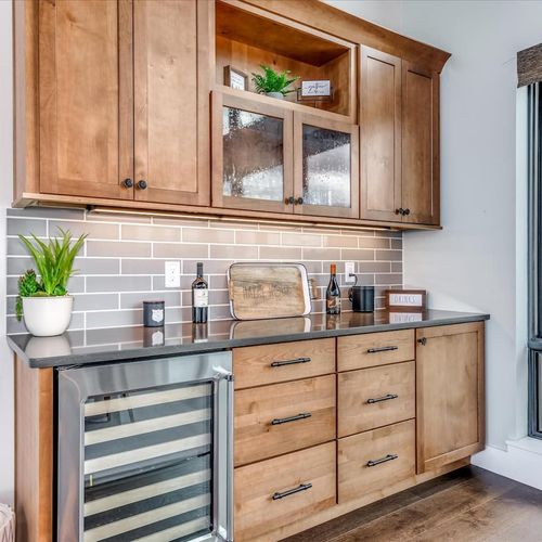 - entertain with ease at the custom wet bar featuring a wine fridge and glass cabinetry
- wood cabinets, subway tile backsplash, and curated accessories elevate the space
- perfect for cocktails, mocktails, or a quiet evening glass of wine