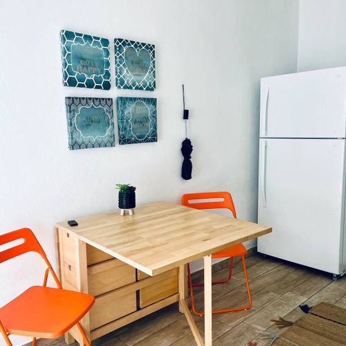 Eco Friendly | Solar Powered Stay 37 Savor your meals in our charming kitchen area, featuring a convenient fridge, a stylish dining table, and tasteful wall art to enhance your culinary experience.
