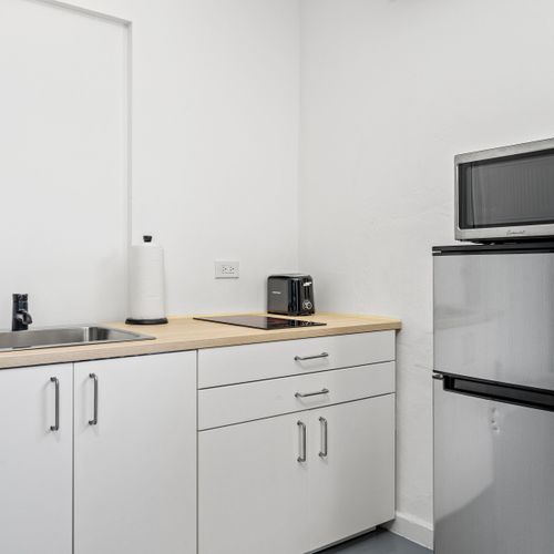 A well-organized kitchen space featuring essential appliances including a digital microwave, an elegant coffee maker, and a sleek induction cooktop.