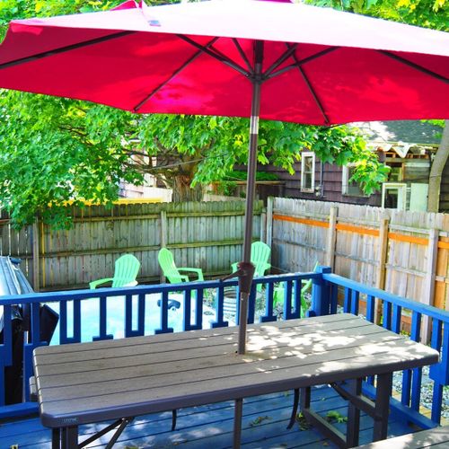 Exterior:  the fully fenced-in backyard with newly expanded deck, new hot tub, bonfire ring, propane grill, and picnic table with umbrella.