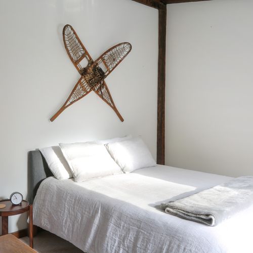 The snowshoe bedroom has a queen bed with luxury linen bedding and features art representative of winter recreation in the Catskills.