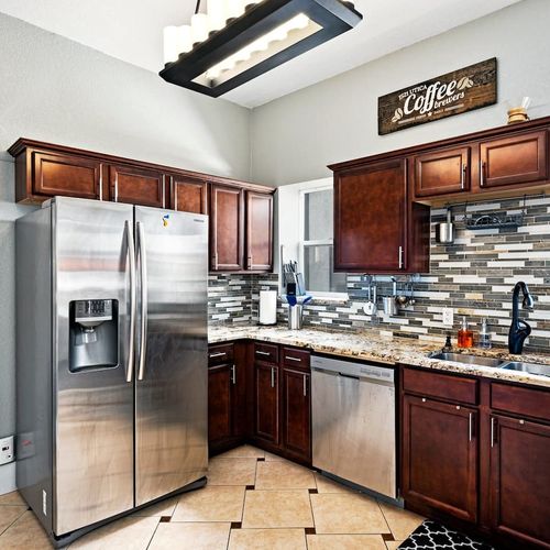 - fully equipped kitchen with stainless steel appliances and granite countertops
- rich wooden cabinetry and a chic backsplash elevate the design appeal
- enjoy morning brews under the playful “coffee” sign above the sink