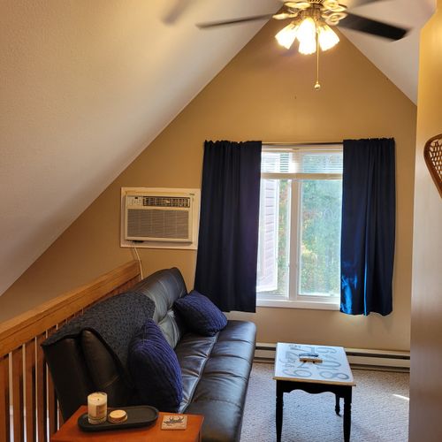 LOFT AREA (SECOND FLOOR):  Very convenient loft area with futon, wall A/C unit, coffee table, chair that unfolds into a bed, and live streaming television (via Sling).