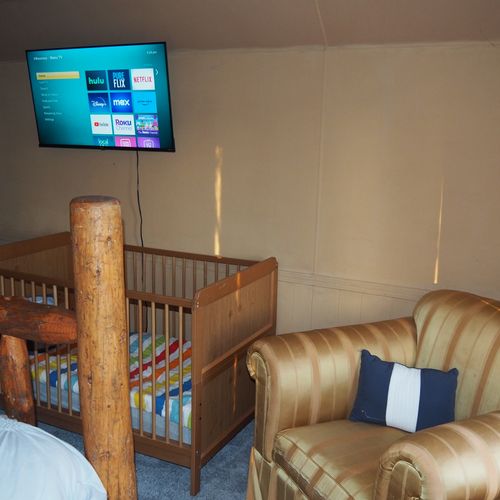 Bedroom #4 (second floor):  features a queen-size bed, private television, sofa bed, comfy chair, ceiling fan, baby crib, and a dresser.