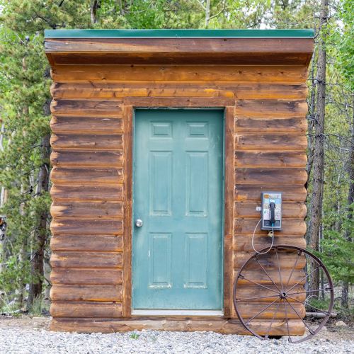 Charming wood shed with teal door and vintage accents, tucked between the trees for a true backwoods feel.