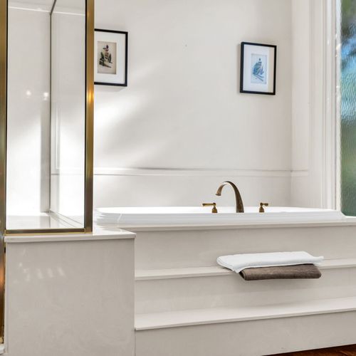 Indulge in relaxation with this inviting soaking tub and elegant gold fixtures.