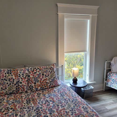 Bedroom #4 (second floor):  features a queen-size bed, twin bed, window a/c unit, ceiling fan, nightstand, lamp, dresser, and a closet.