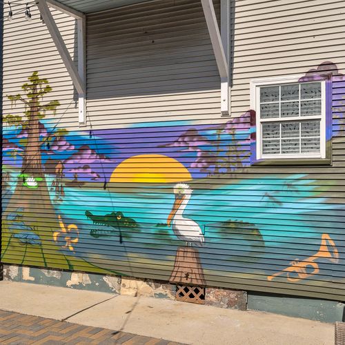 Colorful mural captures the essence of New Orleans with iconic bayou scenery, featuring a pelican, trumpet, and alligator. A perfect backdrop for your stay in the heart of the city.