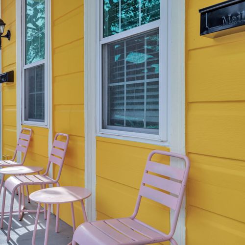 Sunny porch w/ seating & a cheerful yellow façade — soak up that New Orleans charm.