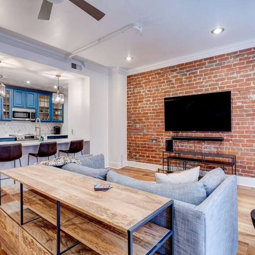 Bright living space w/ exposed brick, hardwood floors & a cozy sectional sofa.