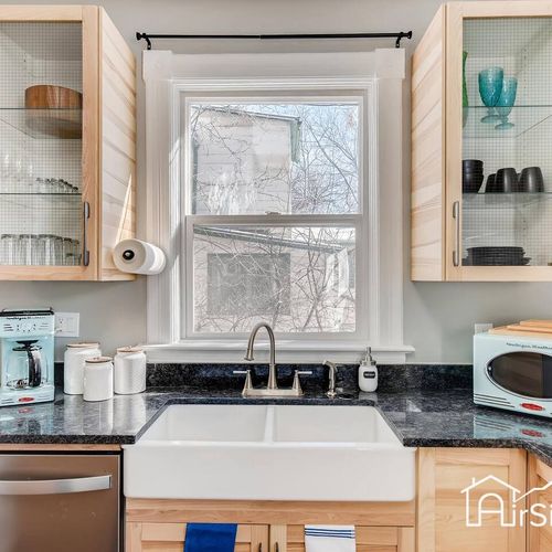 - charming and practical kitchen station with a deep apron front sink and coffee setup
- glass cabinetry adds style while keeping dishes easy to access
- large window brings in light to this cheerful corner of the kitchen