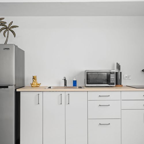Enjoy the ease of cooking with our sleek induction cooktop and state-of-the-art microwave, all set in a bright space with wooden accents.