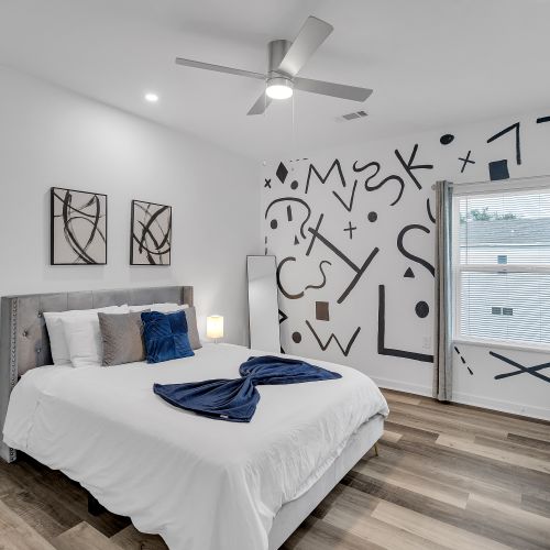 Rest in style with a chic and artistic vibe! This bedroom features a unique mural wall and plush bedding for a comfortable and memorable stay.