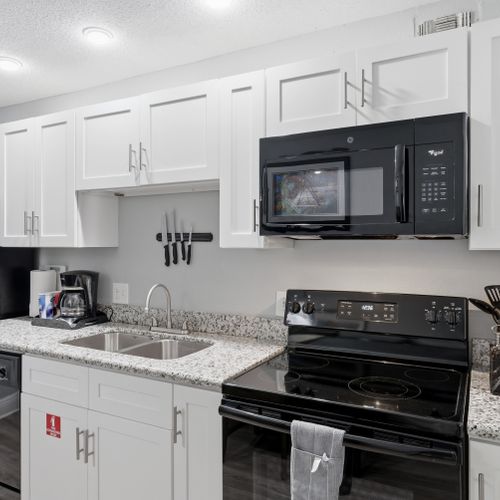 Modern kitchen w/ black appliances & clean white finishes.