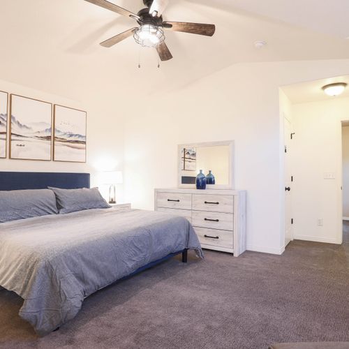 Spacious and serene master bedroom with ceiling fan and soothing hues.