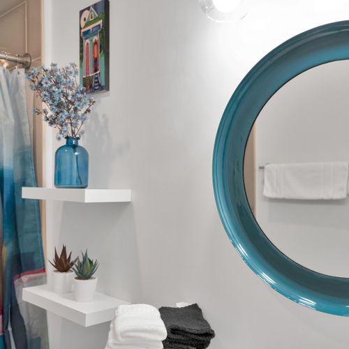 Teal round mirror & blue floral arrangement bring a playful, curated energy.