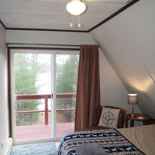 Bedroom #3 (second floor):  features a queen-size bed, walk-out balcony with lakeview, chair, nightstands with lamps, ceiling fan, and a closet.