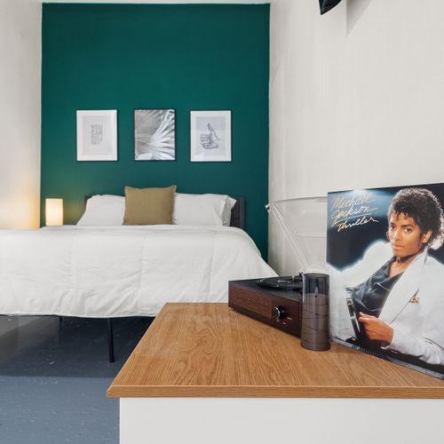 Contemporary bedroom with a soft bed, mounted flat-screen TV, and streams of natural daylight.