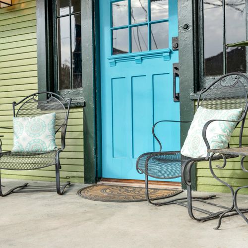 Charming private patio w/ seating framed by a bold teal entry door.